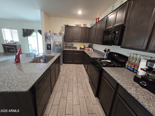 kitchen featuring stone countertops, dark brown cabinets, sink, and black appliances