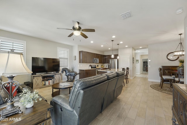 living room featuring sink, ceiling fan with notable chandelier, and light hardwood / wood-style floors