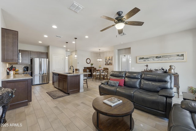 living room featuring ceiling fan, sink, and light wood-type flooring