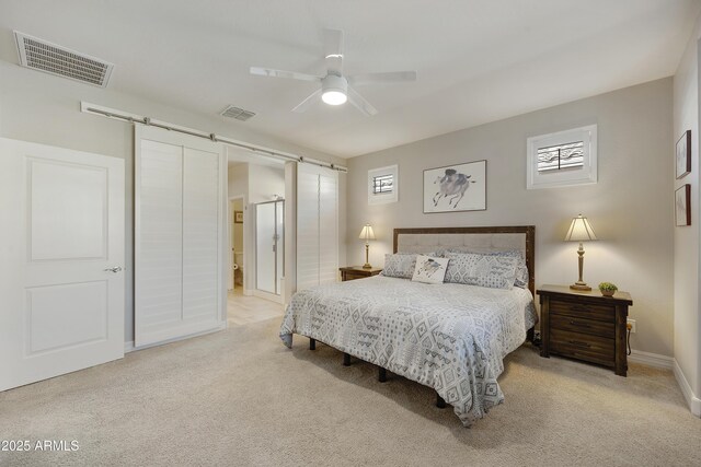 bedroom with light colored carpet, a barn door, and ceiling fan