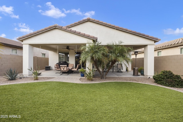 rear view of property featuring ceiling fan, a patio, and a lawn