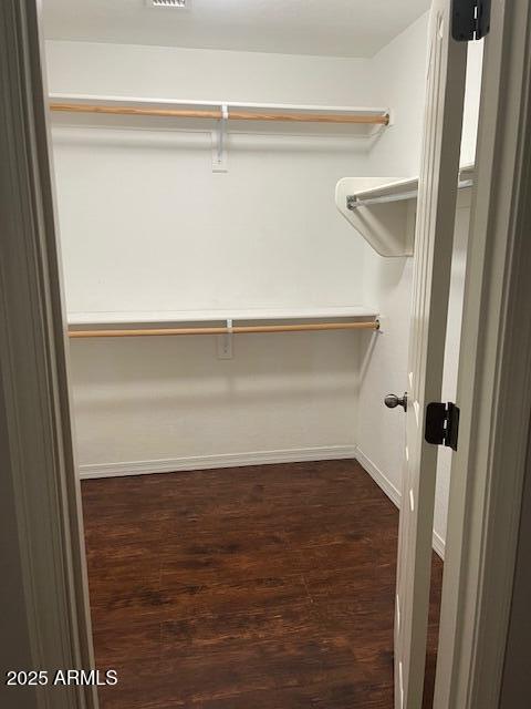 walk in closet with dark wood-type flooring