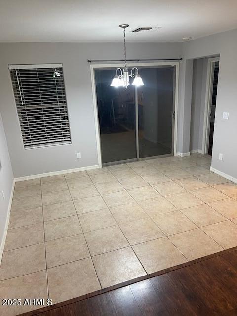 unfurnished dining area featuring light tile patterned floors and a chandelier