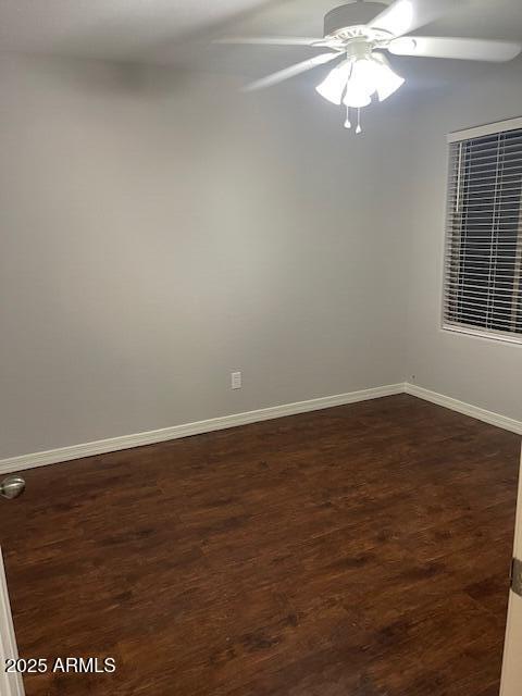 empty room with dark wood-type flooring and ceiling fan