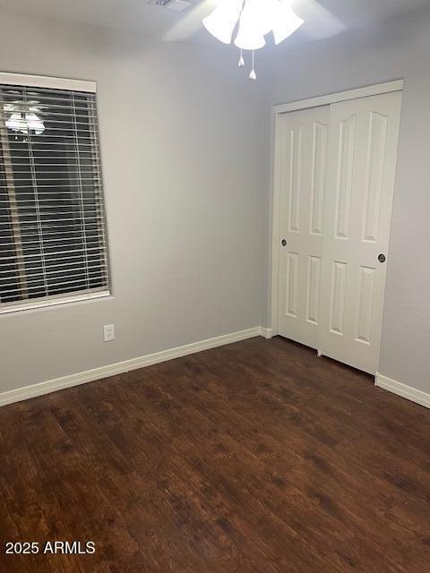 unfurnished bedroom featuring dark hardwood / wood-style flooring, a closet, and ceiling fan