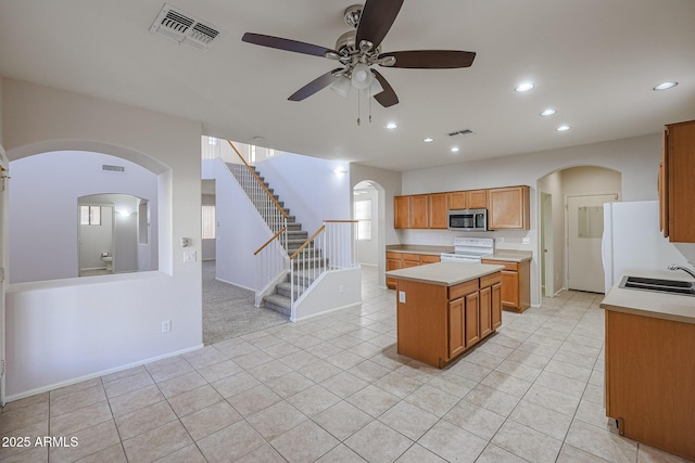 kitchen with ceiling fan, sink, light tile patterned flooring, white appliances, and a kitchen island