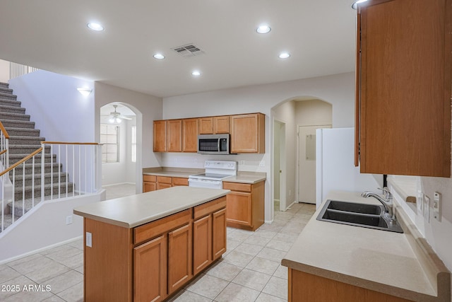 kitchen featuring a center island, sink, ceiling fan, range with electric stovetop, and light tile patterned floors