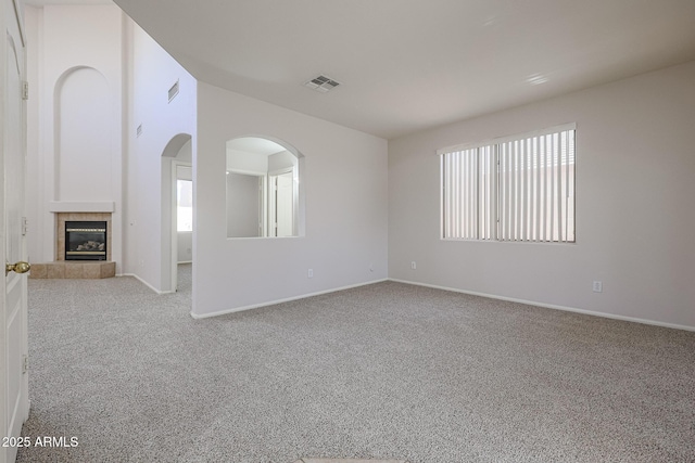 unfurnished living room with a tile fireplace and light carpet