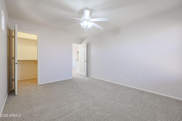 unfurnished bedroom featuring ceiling fan, a spacious closet, light carpet, and a closet