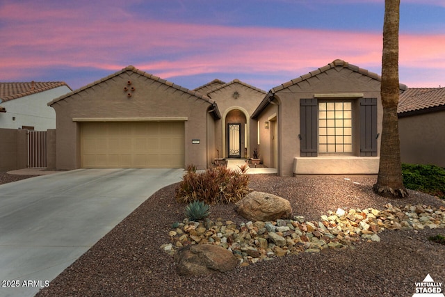 view of front of house featuring a garage, a tile roof, driveway, and stucco siding