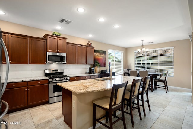 kitchen with visible vents, a notable chandelier, a sink, backsplash, and appliances with stainless steel finishes