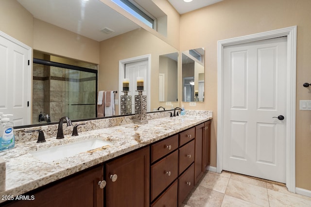 bathroom featuring double vanity, tile patterned flooring, a shower stall, and a sink