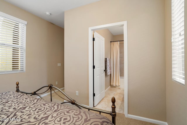 bedroom featuring multiple windows, baseboards, and light carpet