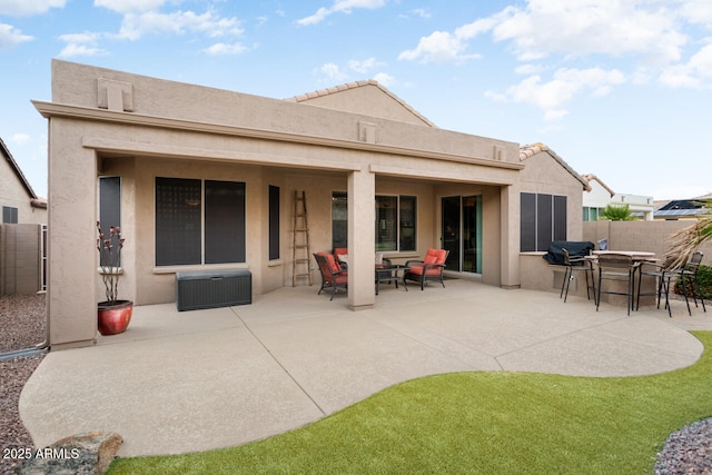 rear view of house featuring stucco siding, fence, and a patio area