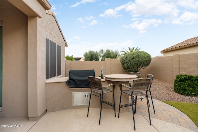 view of patio featuring outdoor dining area, fence, and grilling area