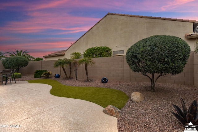 yard at dusk featuring a patio area and a fenced backyard