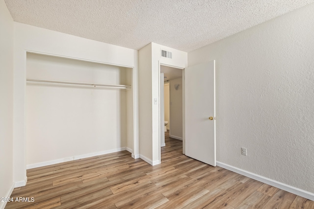 unfurnished bedroom with a textured ceiling, a closet, and light wood-type flooring