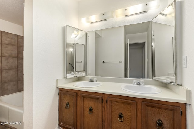 bathroom featuring shower / washtub combination, vanity with extensive cabinet space, a textured ceiling, and double sink