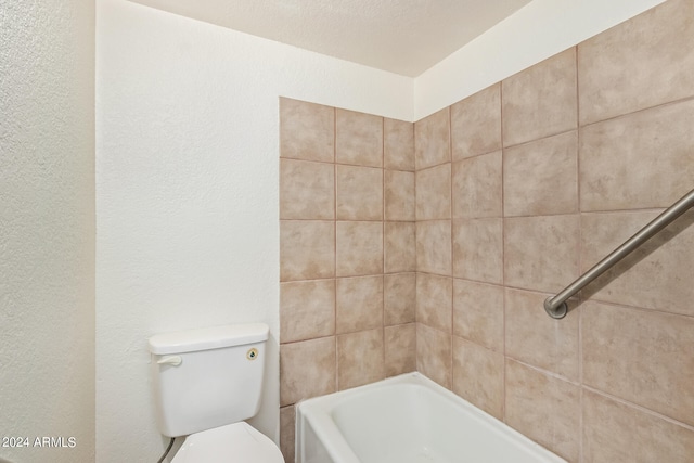 bathroom featuring tiled shower / bath, a textured ceiling, and toilet