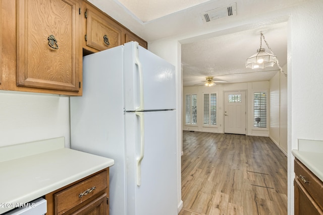 kitchen with decorative light fixtures, white fridge, ceiling fan, light wood-type flooring, and a textured ceiling