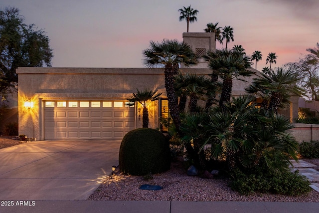 view of front facade with a garage, concrete driveway, and stucco siding