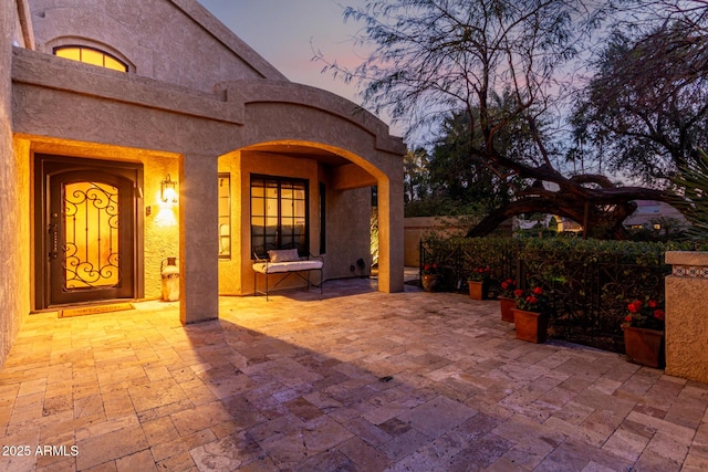 exterior entry at dusk featuring a patio area and stucco siding