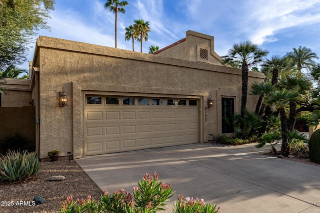 exterior space featuring a garage, driveway, and stucco siding