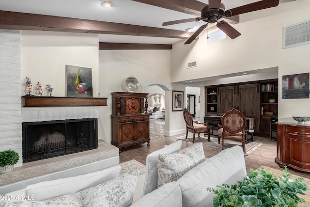 living room with vaulted ceiling with beams, a fireplace, visible vents, and light wood-style floors