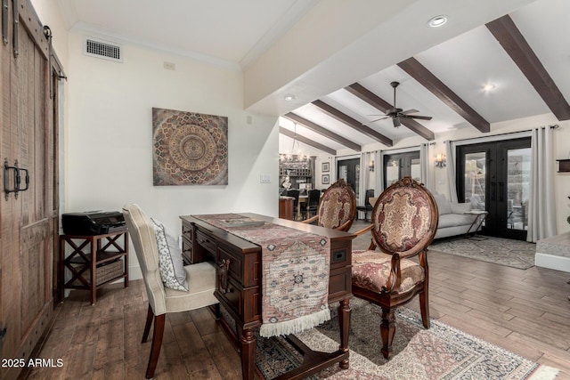 dining room with a barn door, visible vents, wood finished floors, vaulted ceiling with beams, and ceiling fan with notable chandelier