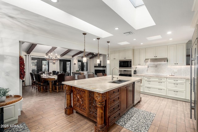 kitchen with a skylight, stainless steel appliances, visible vents, decorative backsplash, and a sink