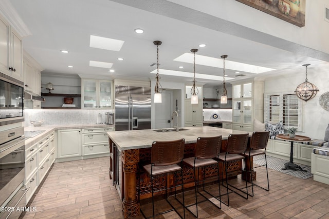 kitchen featuring a skylight, light countertops, open shelves, and built in appliances