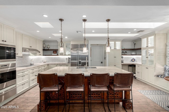 kitchen featuring black appliances, a skylight, open shelves, and a kitchen island with sink