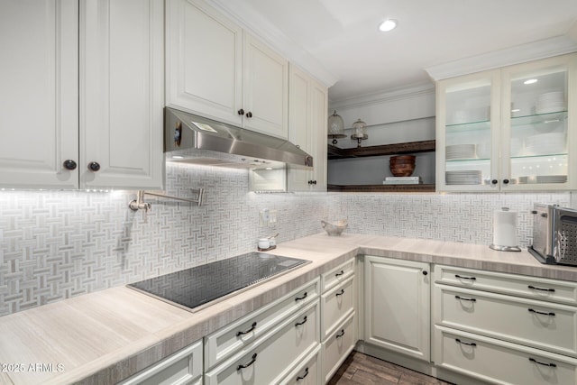 kitchen with light countertops, backsplash, black electric cooktop, and under cabinet range hood