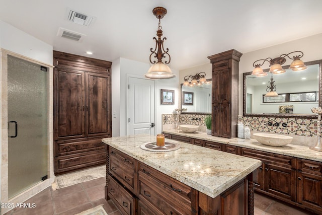 full bathroom featuring a sink, tasteful backsplash, a shower stall, and visible vents