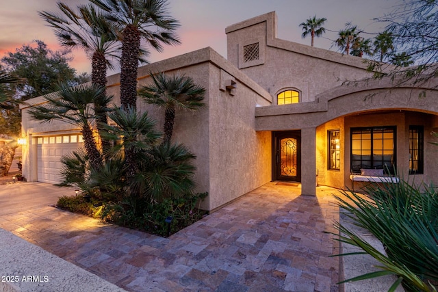 view of front of property with a garage, driveway, and stucco siding