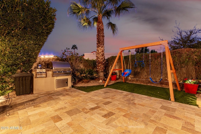 view of patio with a playground, a grill, and an outdoor kitchen