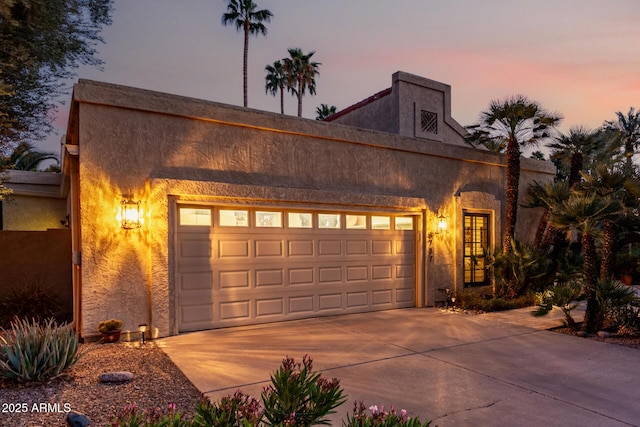 view of front facade featuring driveway, an attached garage, and stucco siding