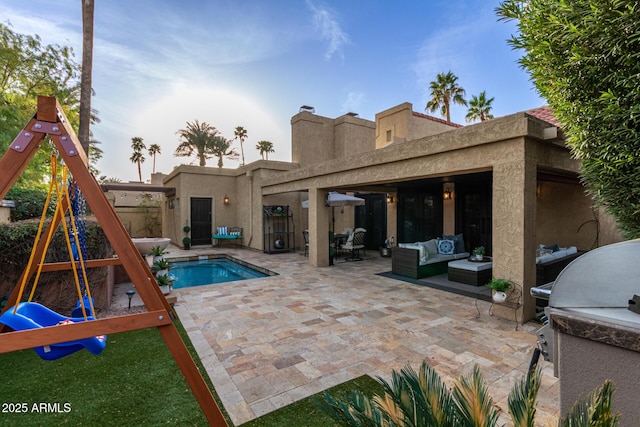 rear view of property featuring a playground, outdoor lounge area, stucco siding, an outdoor pool, and a patio area