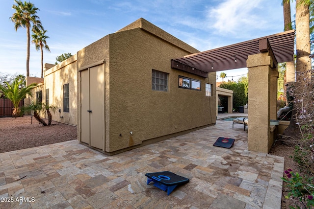 exterior space featuring a pergola, a patio, fence, and stucco siding