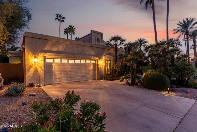 view of front of property with a garage, driveway, and stucco siding