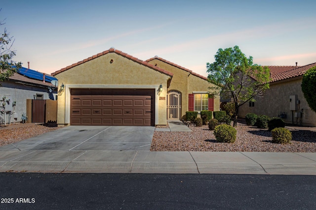 mediterranean / spanish-style home with a tiled roof, stucco siding, driveway, and an attached garage