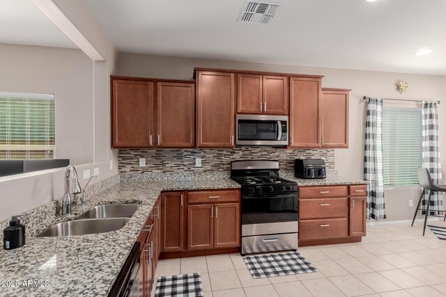 kitchen with gas stove, stainless steel microwave, tasteful backsplash, and a sink