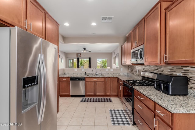 kitchen with a sink, visible vents, appliances with stainless steel finishes, and brown cabinetry