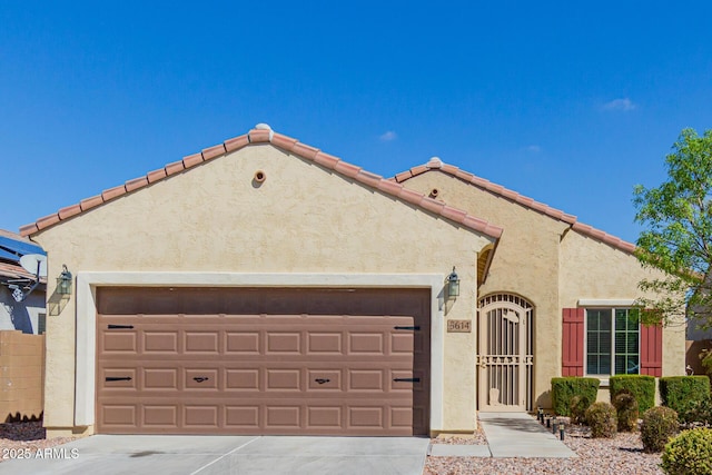 mediterranean / spanish-style home featuring stucco siding, a garage, concrete driveway, and a tile roof