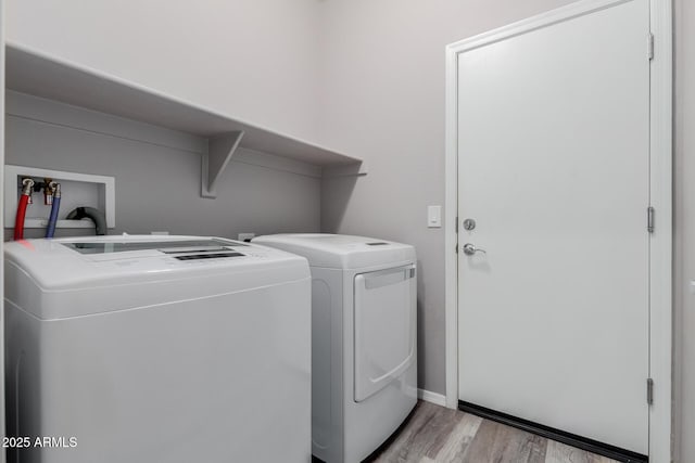 washroom featuring baseboards, separate washer and dryer, light wood-style flooring, and laundry area