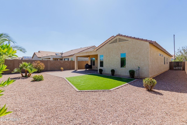 back of house with a tiled roof, stucco siding, a fenced backyard, a yard, and a patio