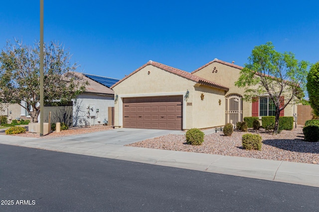 mediterranean / spanish house featuring stucco siding, concrete driveway, an attached garage, and a tile roof