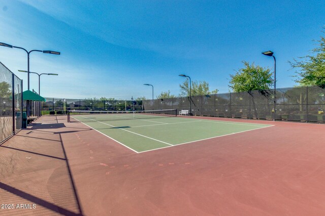 view of tennis court with community basketball court and fence