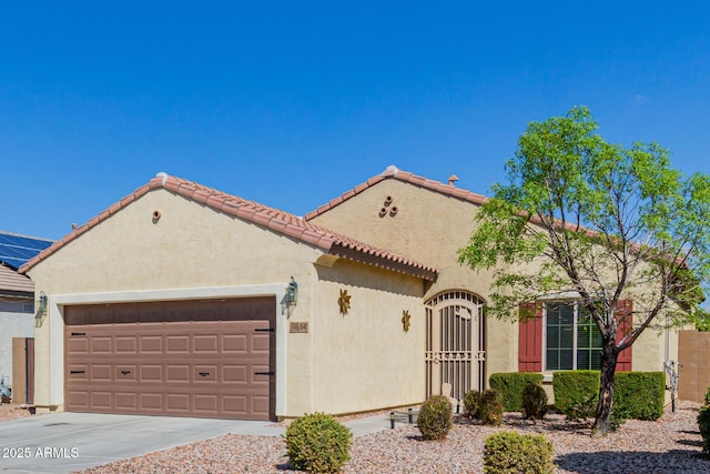 mediterranean / spanish-style home featuring stucco siding, a garage, driveway, and a tile roof