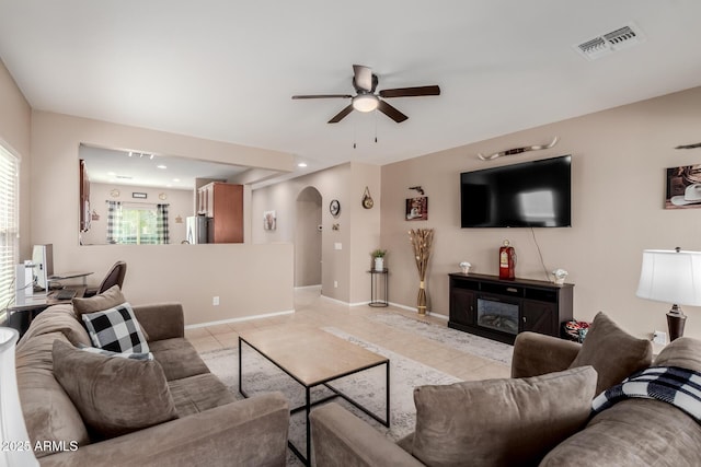 living area with light tile patterned floors, visible vents, arched walkways, and a glass covered fireplace